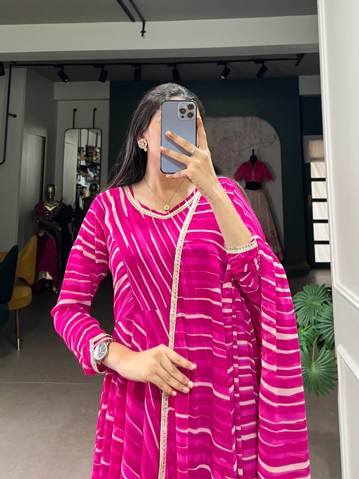 Woman taking a mirror selfie wearing a pink and white striped dress in an indoor setting.