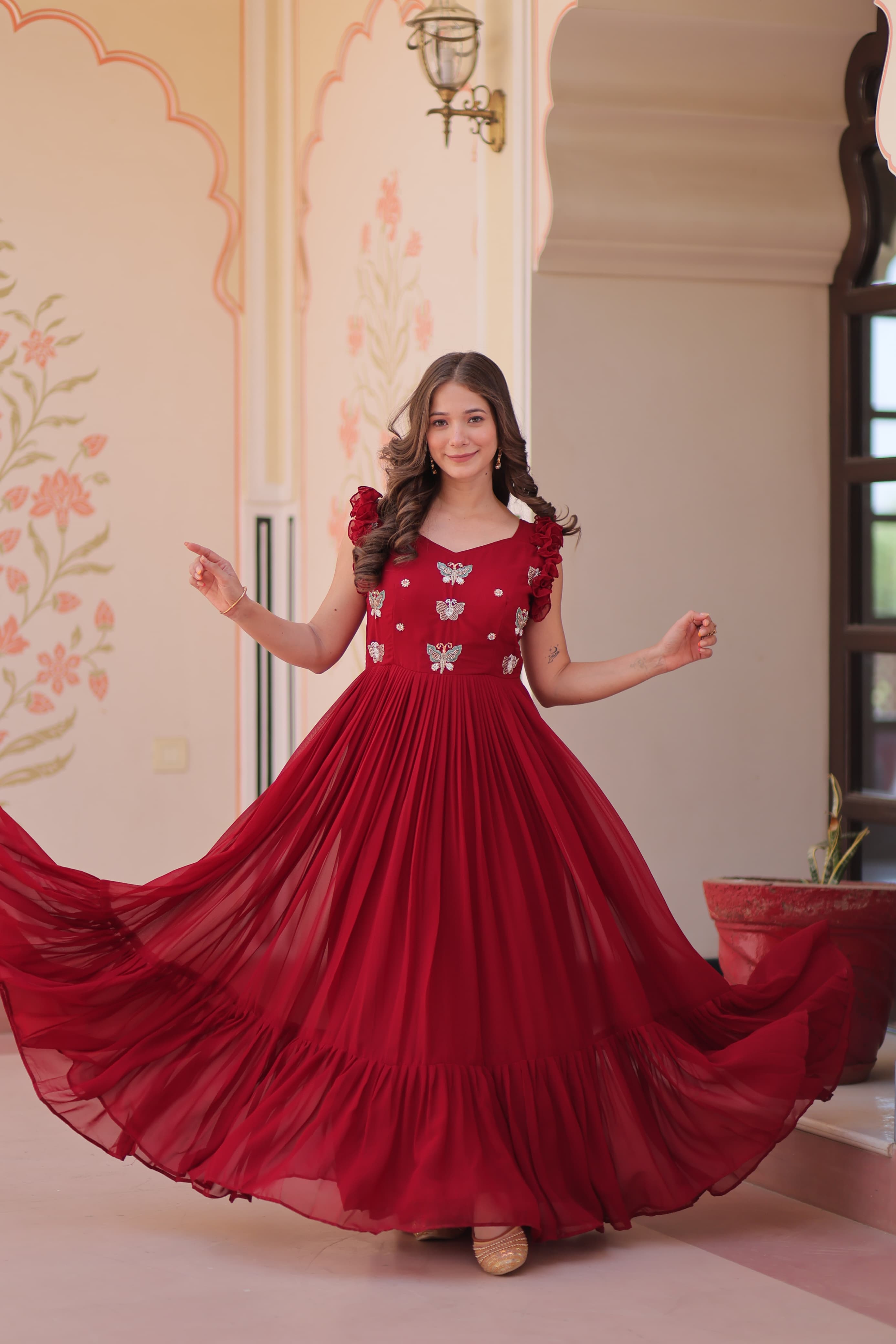 Woman in a red dress with floral patterns standing in a decorated room.