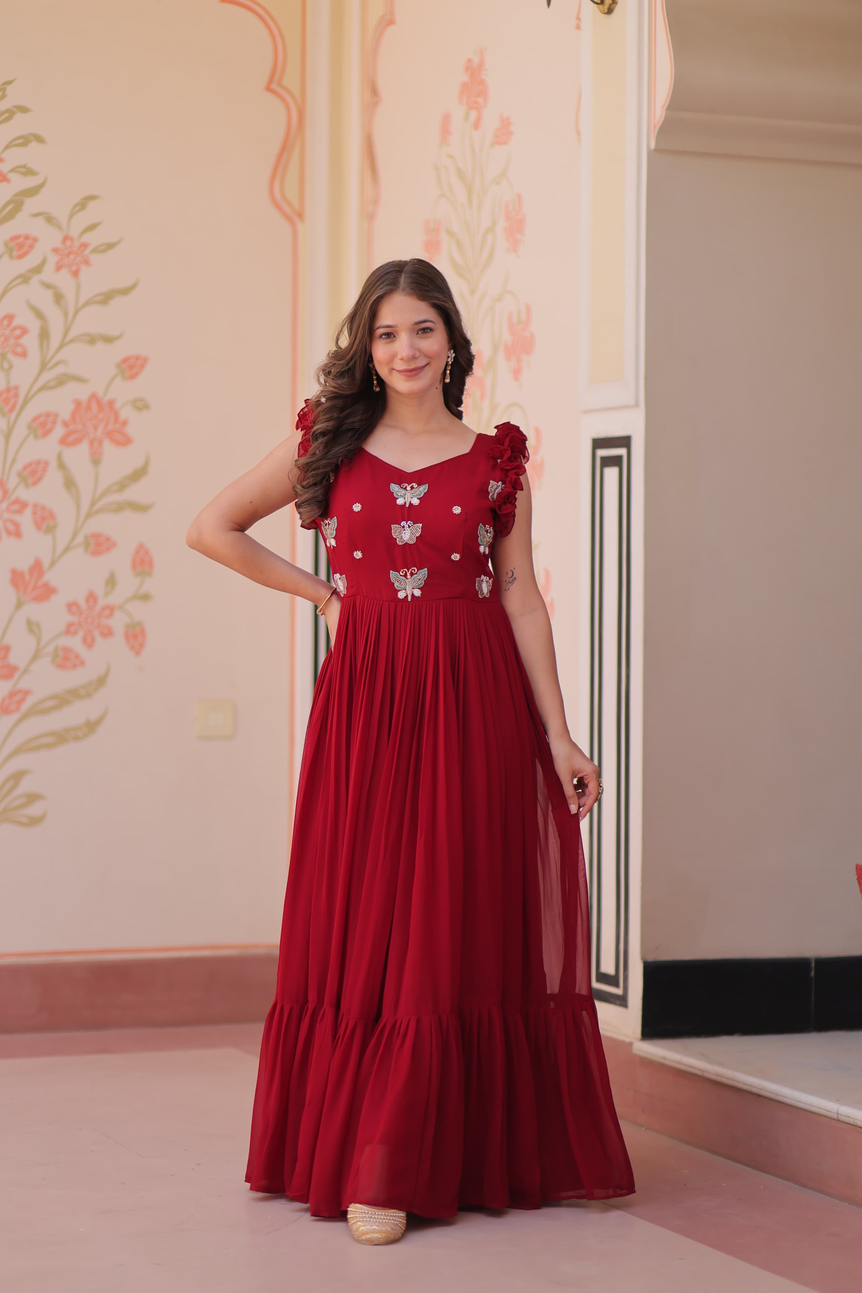 Woman wearing a red dress with floral patterns in an indoor setting.