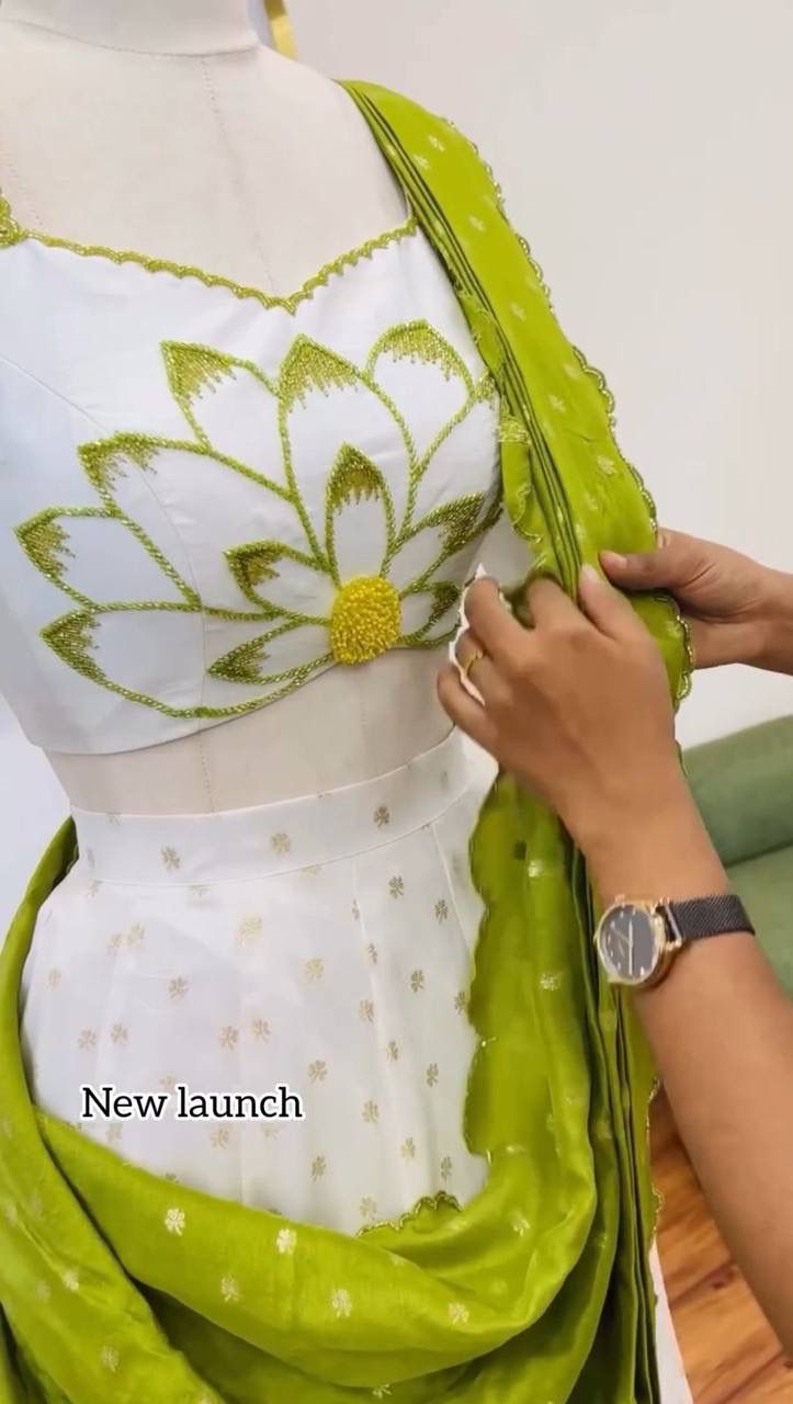 Green and white saree with a floral pattern on a mannequin, held by a person.