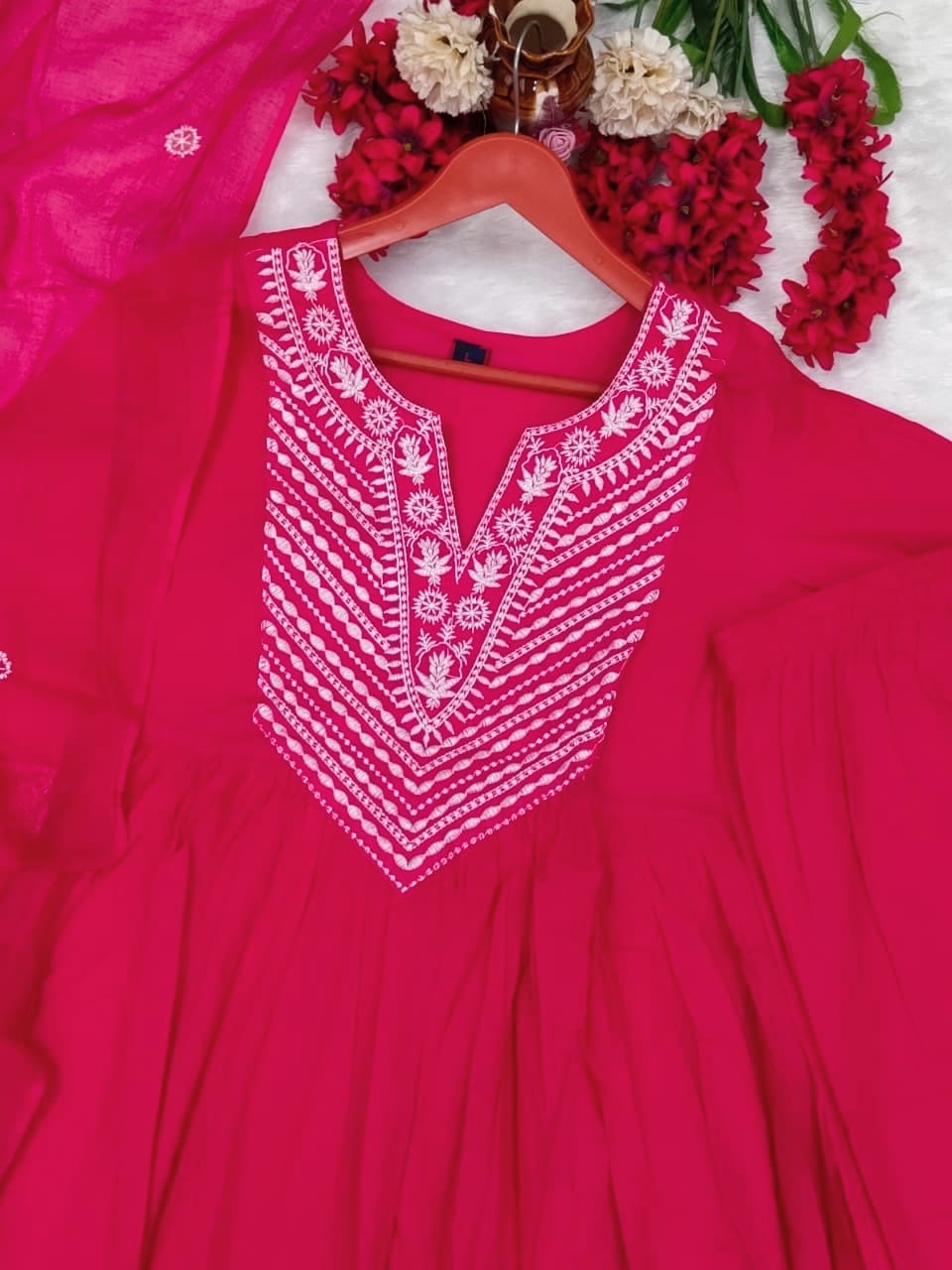 Pink embroidered dress on a hanger with flowers in the background