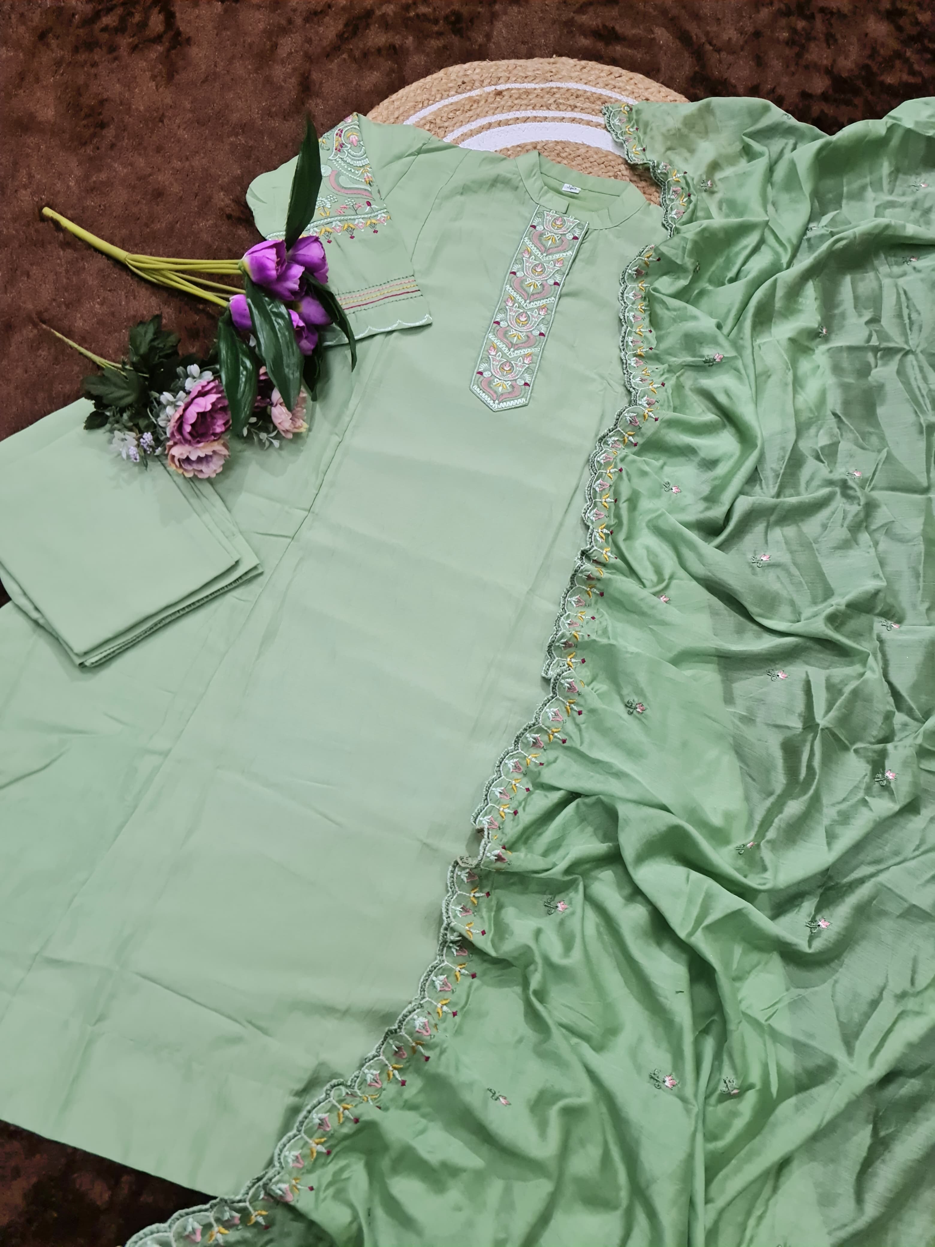 Green embroidered saree with a floral arrangement on a brown surface