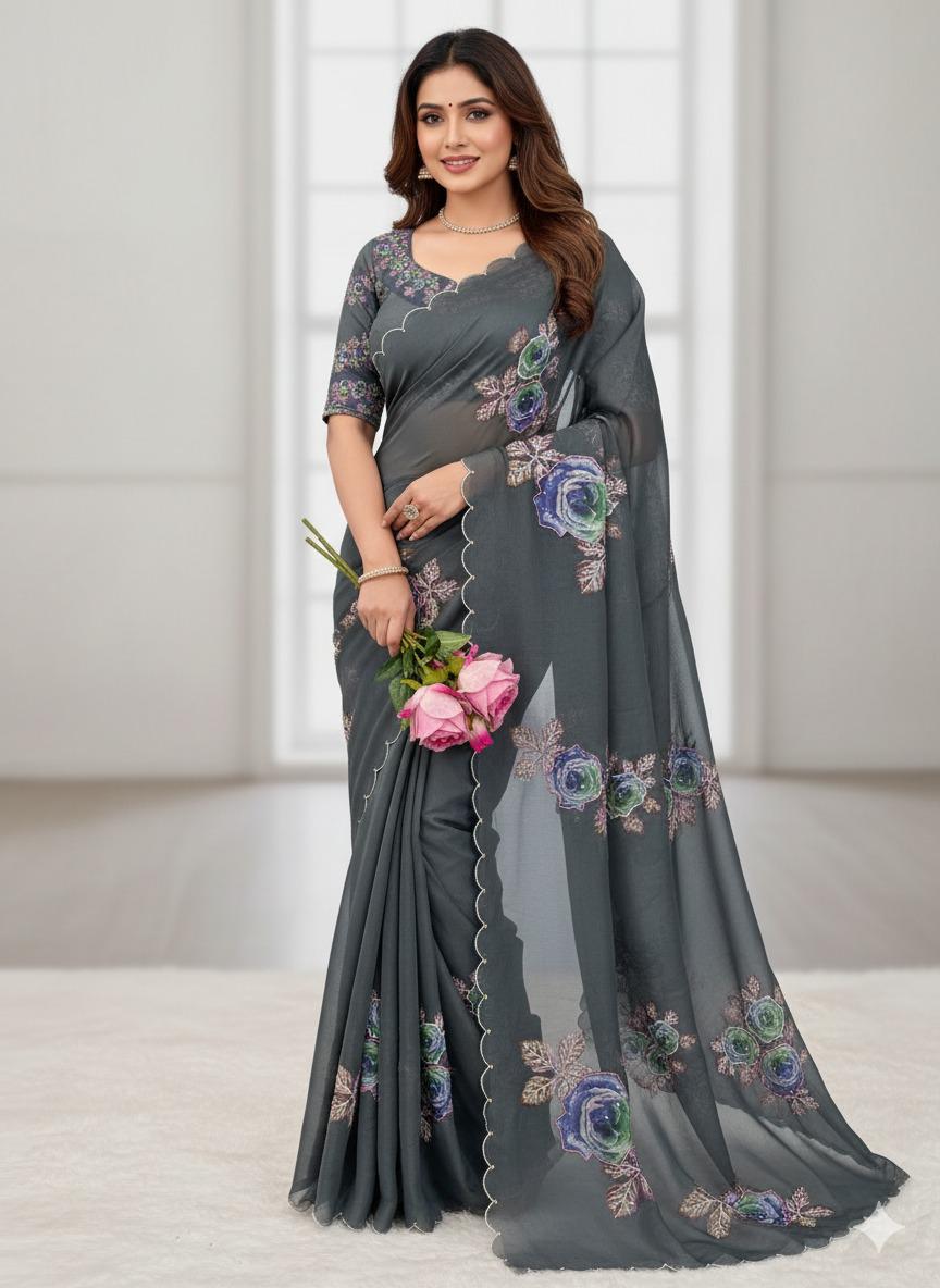 Woman wearing a gray saree with floral patterns holding pink flowers indoors.