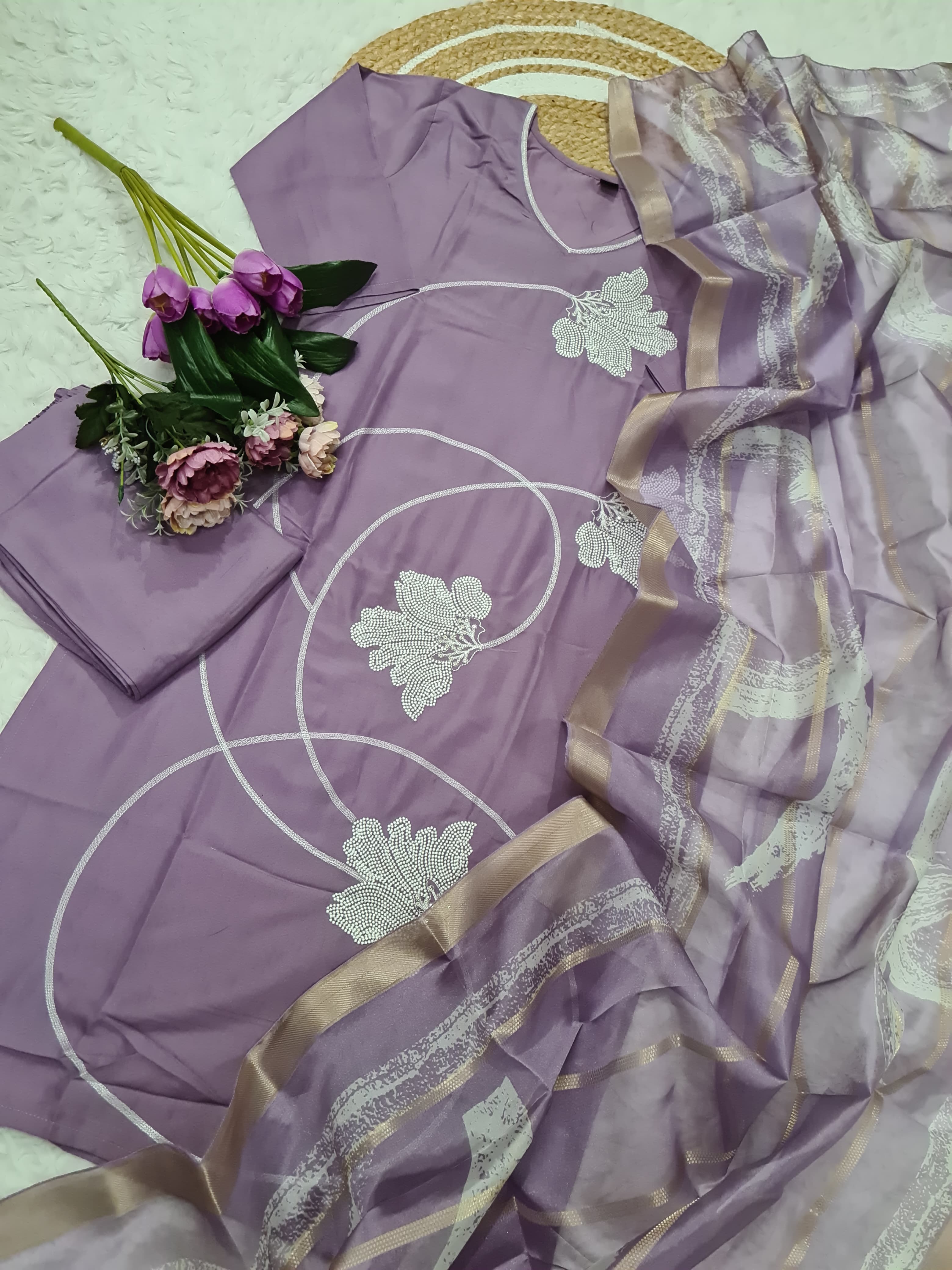 Purple saree with floral patterns and a matching blouse on a light green background