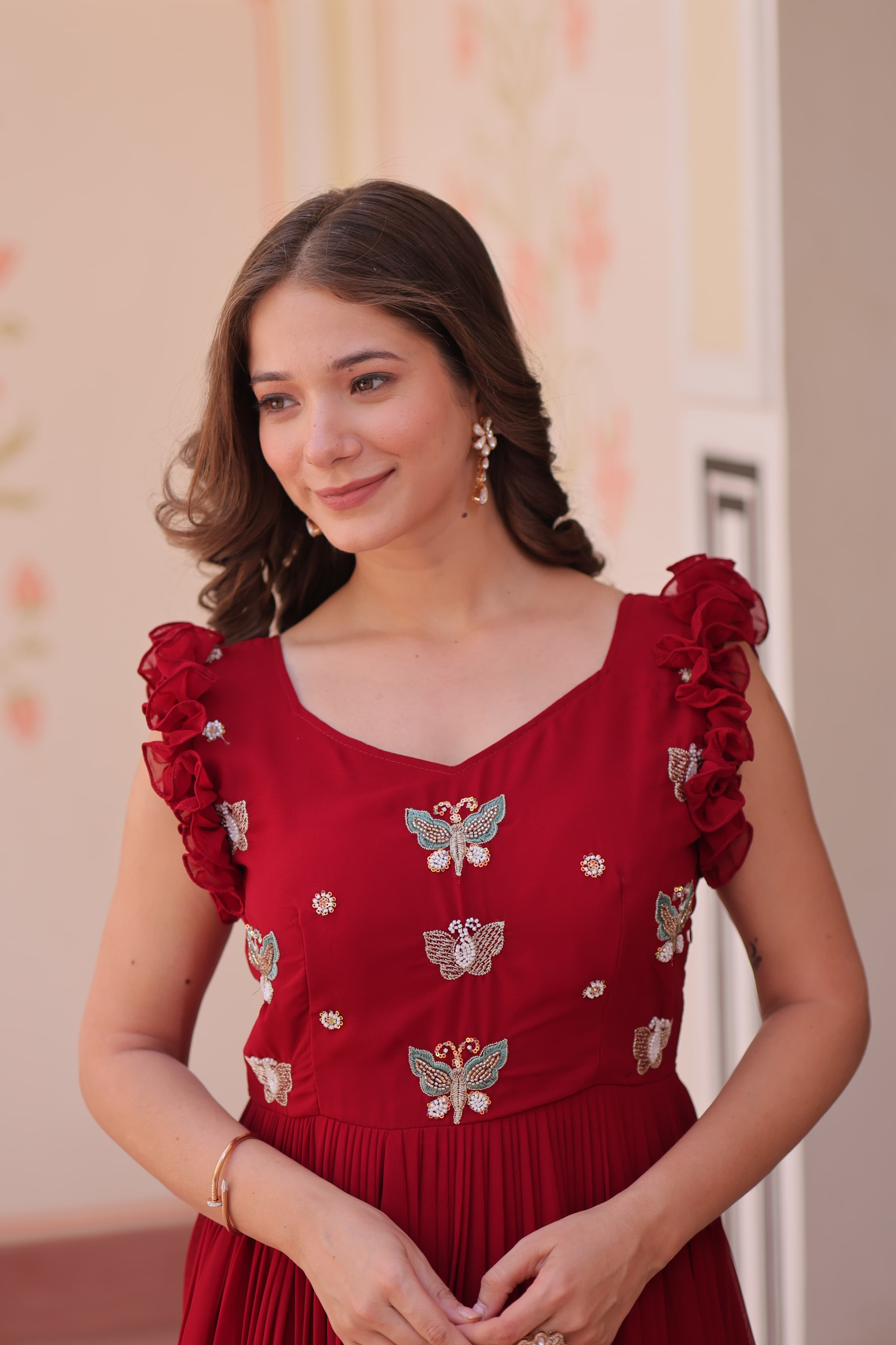 Woman wearing a red dress with butterfly patterns in an indoor setting